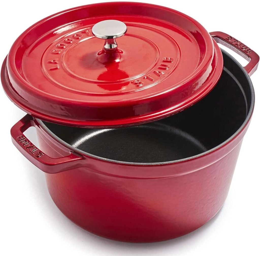 A red cast iron Dutch oven with an open lid, perfect for crafting flavorful fall soup recipes, featuring side handles and a knob on the lid's top.