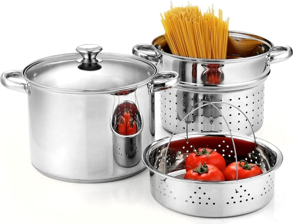 Stainless steel cookware set perfect for fall soup recipes, featuring a large pot with lid, a colander filled with tomatoes, and a pot ready for uncooked spaghetti.