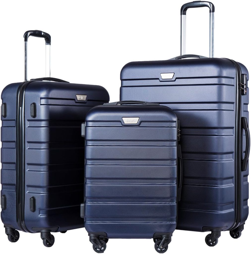 Three navy blue hard-shell suitcases with retractable handles and four wheels, arranged from smallest to largest, resemble stacked Halloween sugar cookies in their neat order.