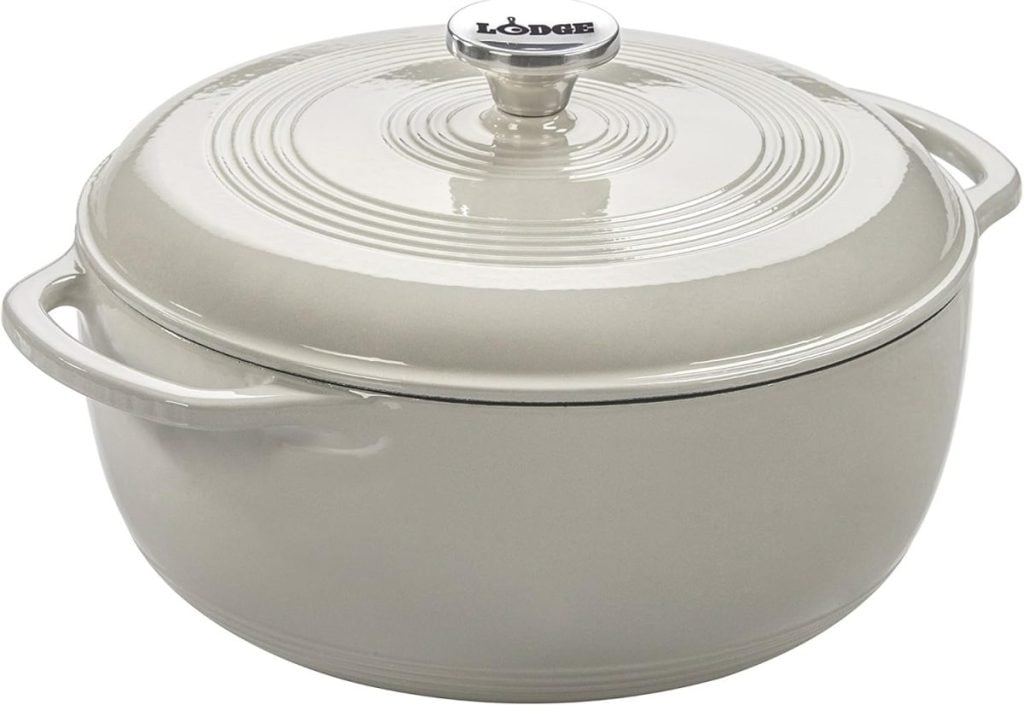 A beige enameled cast iron Dutch oven with a lid and handles, ideal for crafting your favorite fall soup recipes. This Lodge-branded piece features a top knob, making it both functional and stylish for autumn cooking.