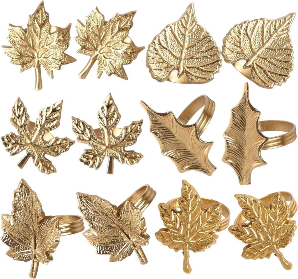 Twelve gold leaf-shaped napkin rings, reminiscent of fall's cozy charm, are artfully arranged in rows against a white background.