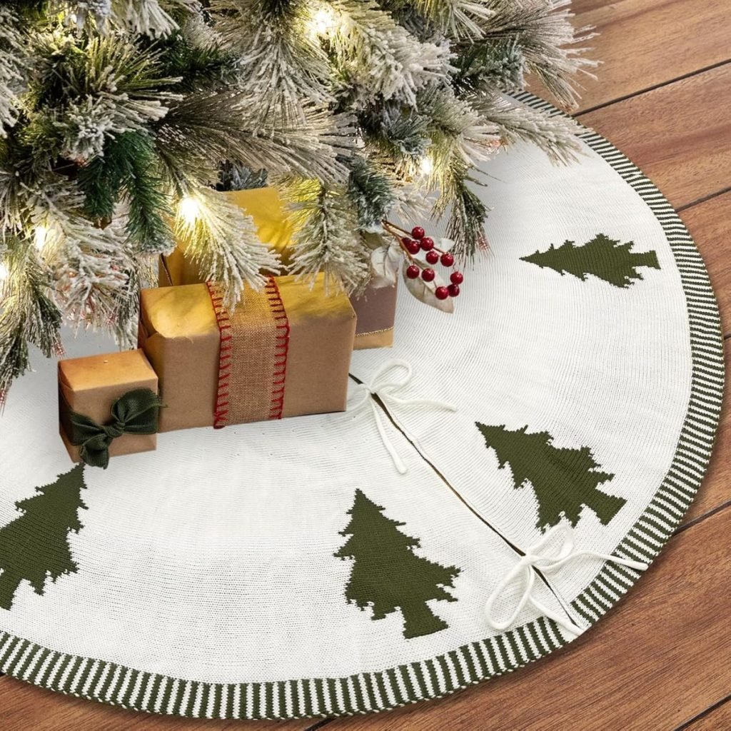 A Christmas tree with frosted branches and glowing lights stands above a circular white tree skirt with green patterns, resembling a cozy fall blanket. Presents wrapped in brown paper sit invitingly on the skirt.