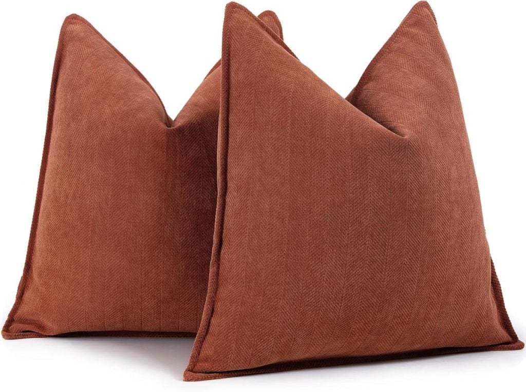 Two brown square cushions with a herringbone pattern, perfect as fall pillows, are placed side by side.