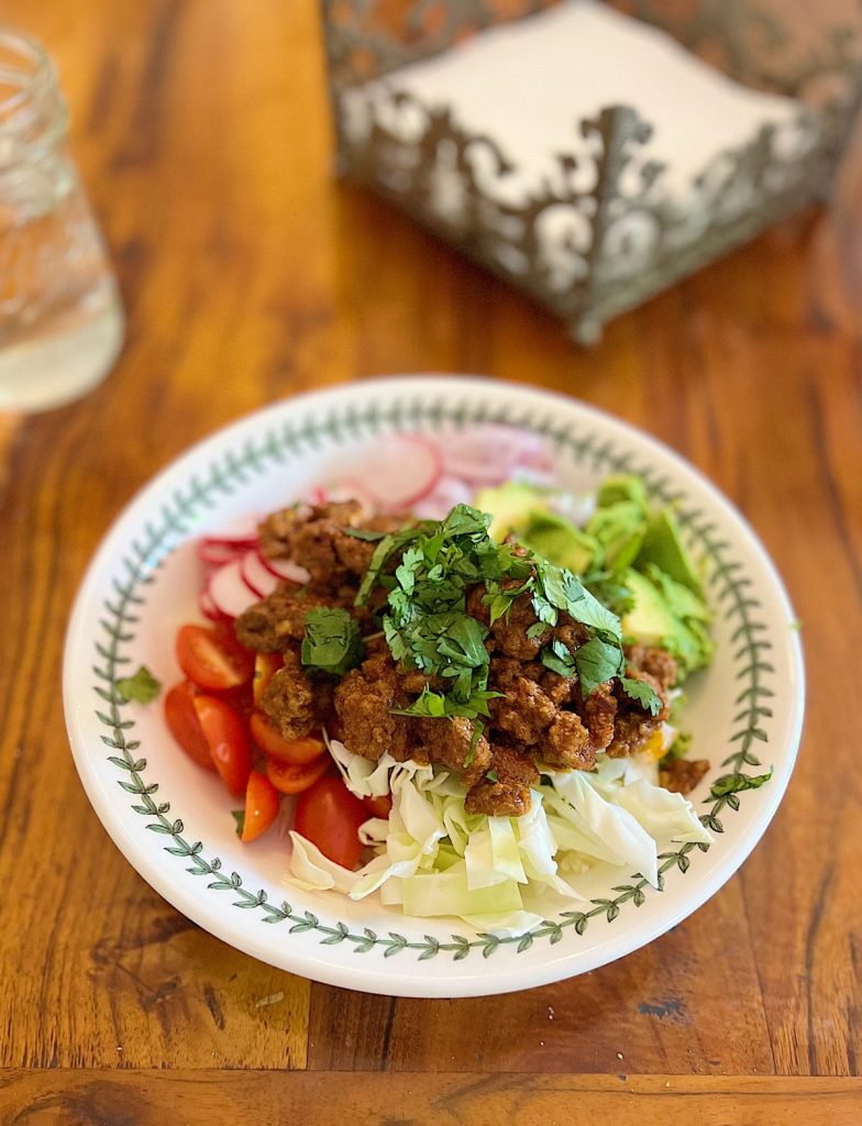 Keto Beef Taco bowl with beef, cabbage, tomatoes, red onions, radishes, and avocados.
