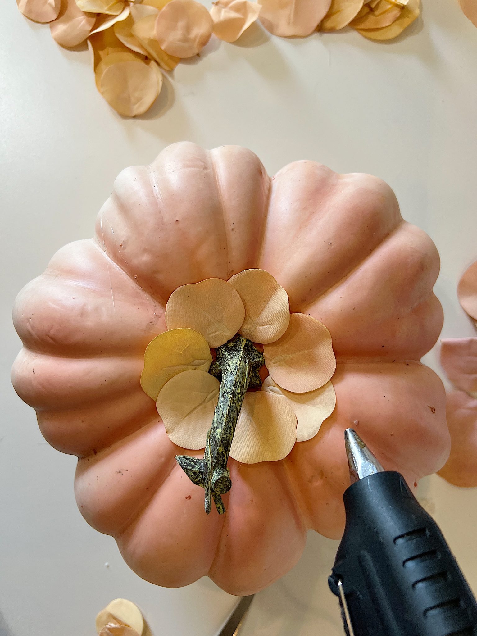 A handmade pumpkin made with a plastic cinderella pumpkin covered with faux eucalyptus leaves.
