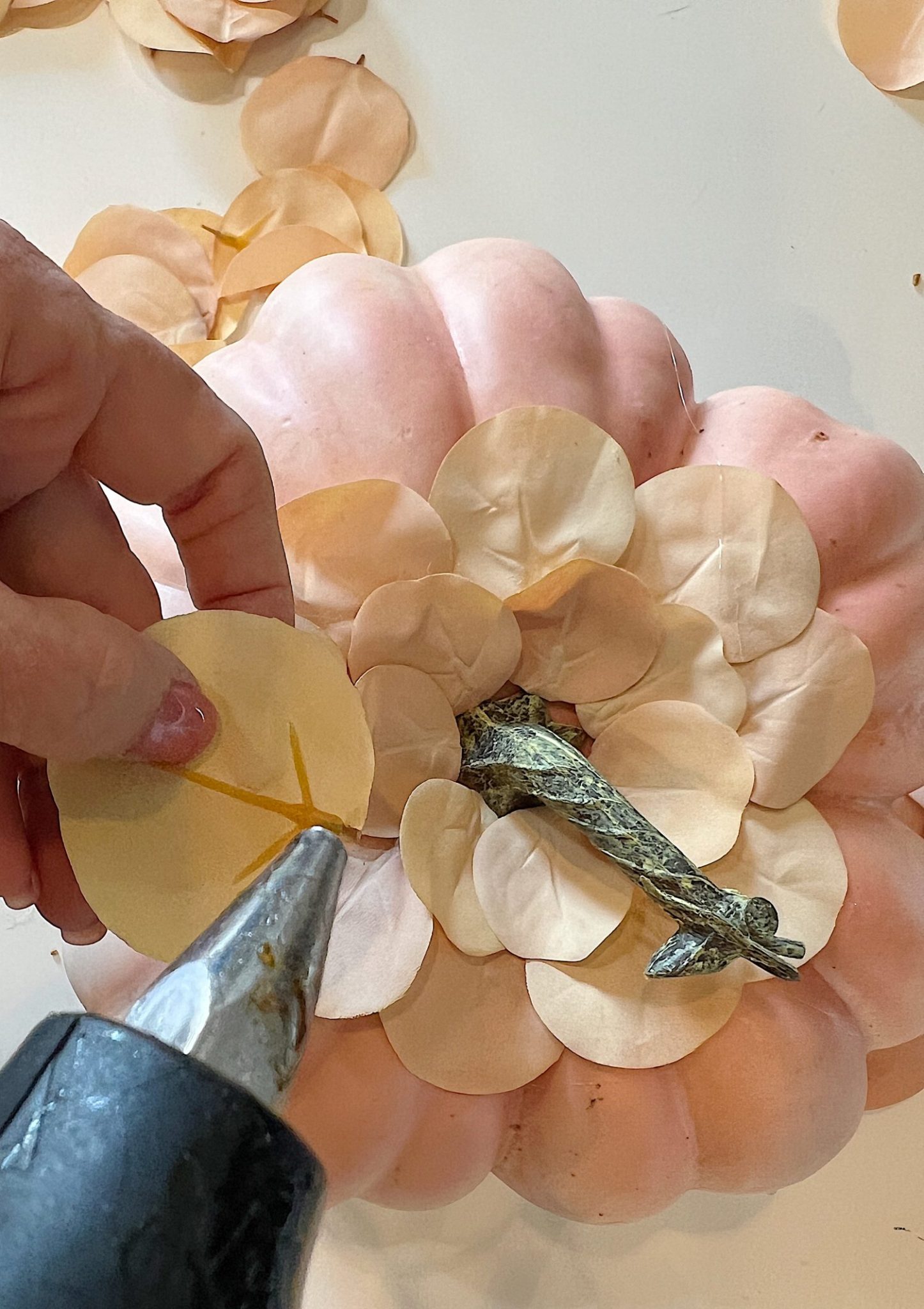 A handmade pumpkin made with a plastic cinderella pumpkin covered with faux eucalyptus leaves.