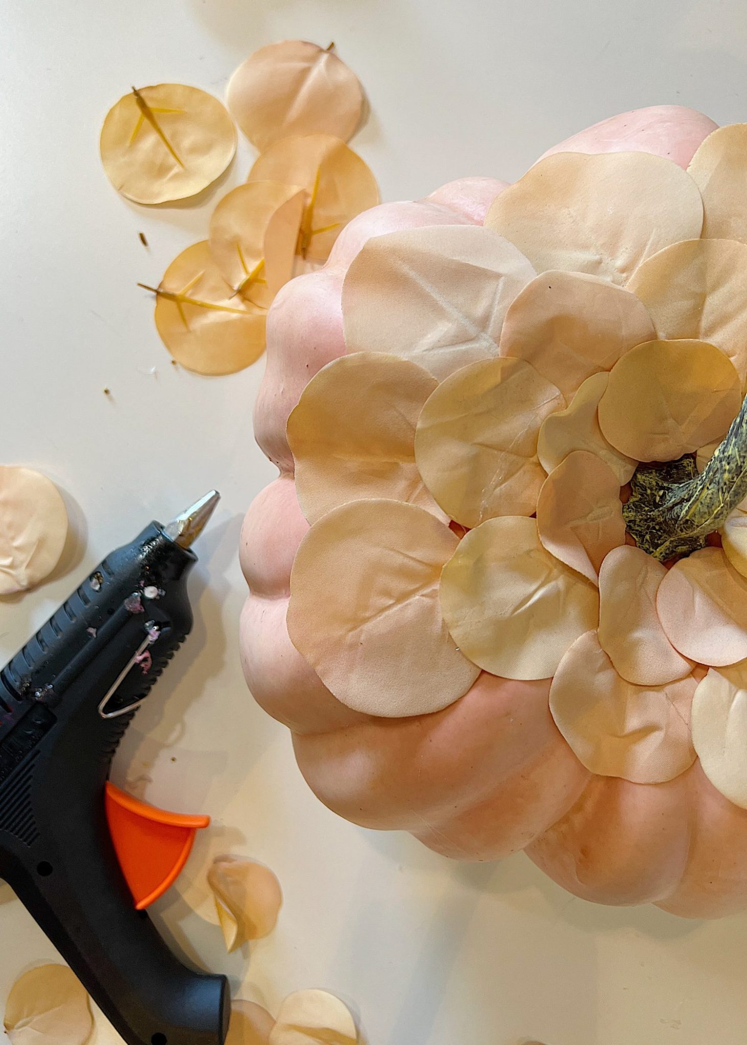 A handmade pumpkin made with a plastic cinderella pumpkin covered with faux eucalyptus leaves.