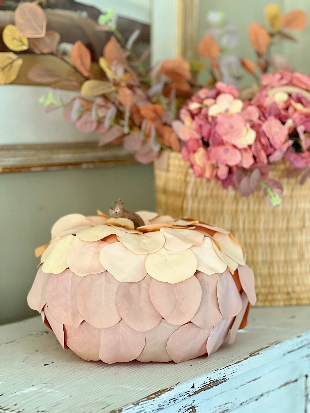 A handmade pumpkin made with a plastic cinderella pumpkin covered with faux eucalyptus leaves.