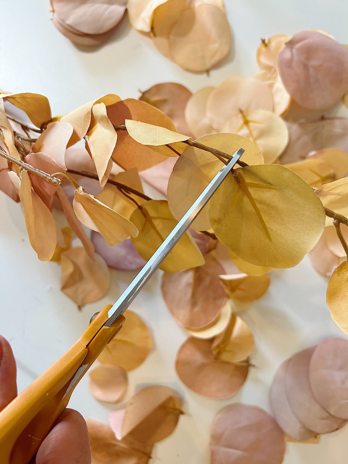 A handmade pumpkin made with a plastic cinderella pumpkin covered with faux eucalyptus leaves.