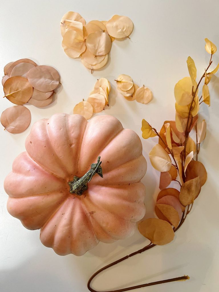 A handmade pumpkin made with a plastic cinderella pumpkin covered with faux eucalyptus leaves.