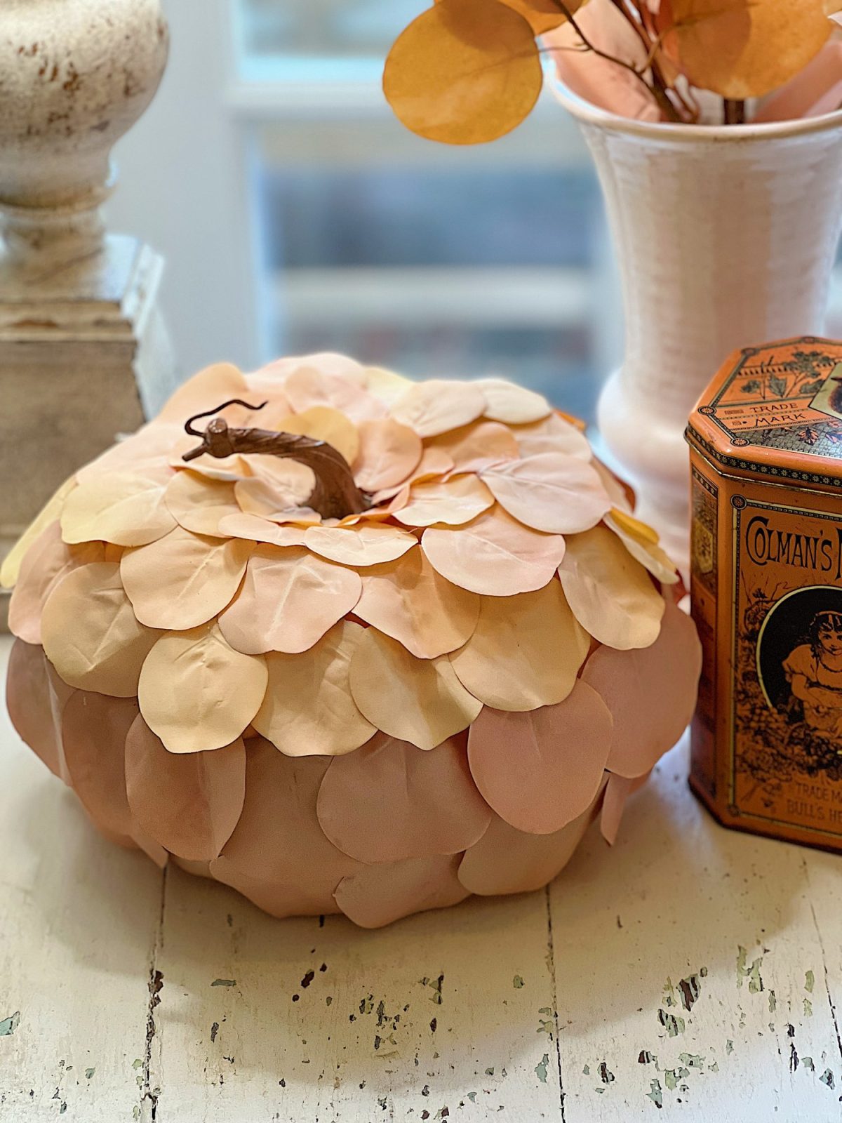 A handmade pumpkin made with a plastic cinderella pumpkin covered with faux eucalyptus leaves.