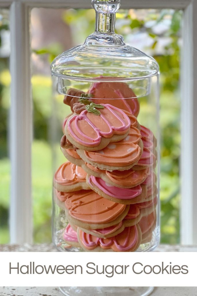 Decorated Pumpkin-shaped sugar cookies in a tall apothecary jar.