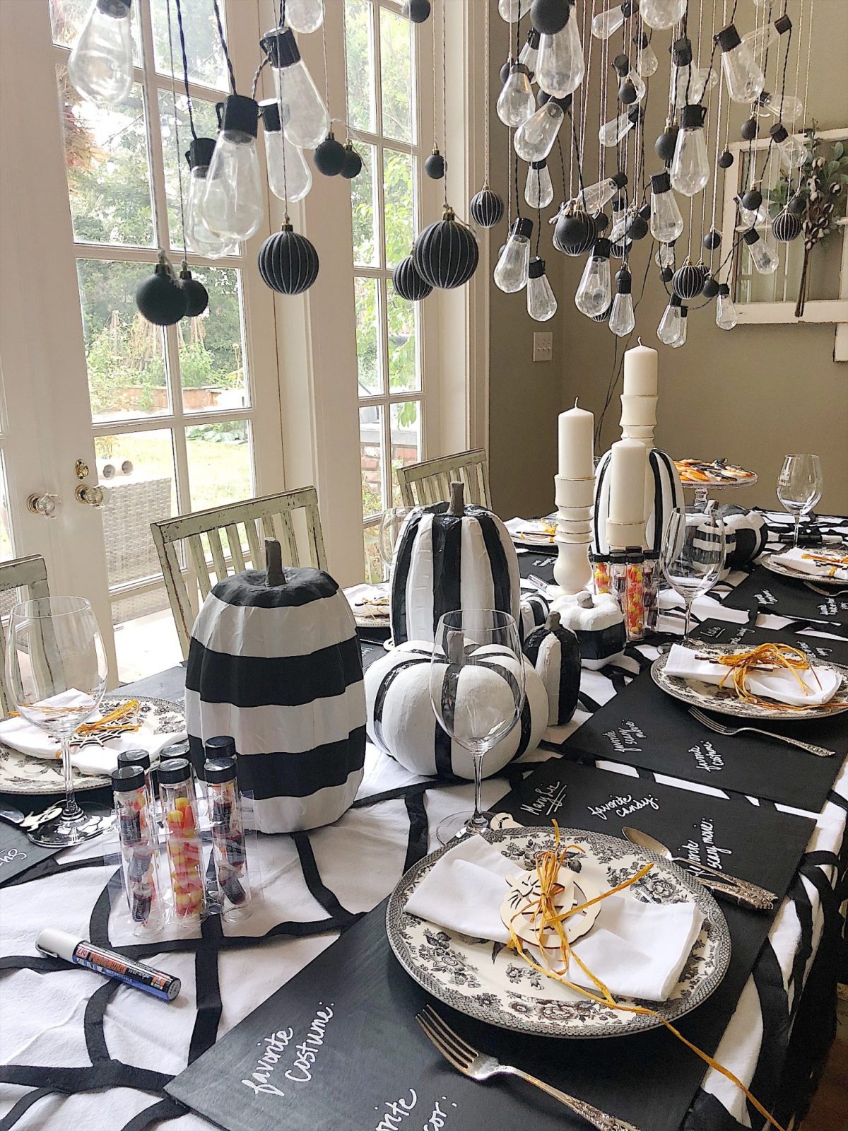 A Halloween table decorated with lights, a spider web, chalkboards, candles, cookies, candy, and more.