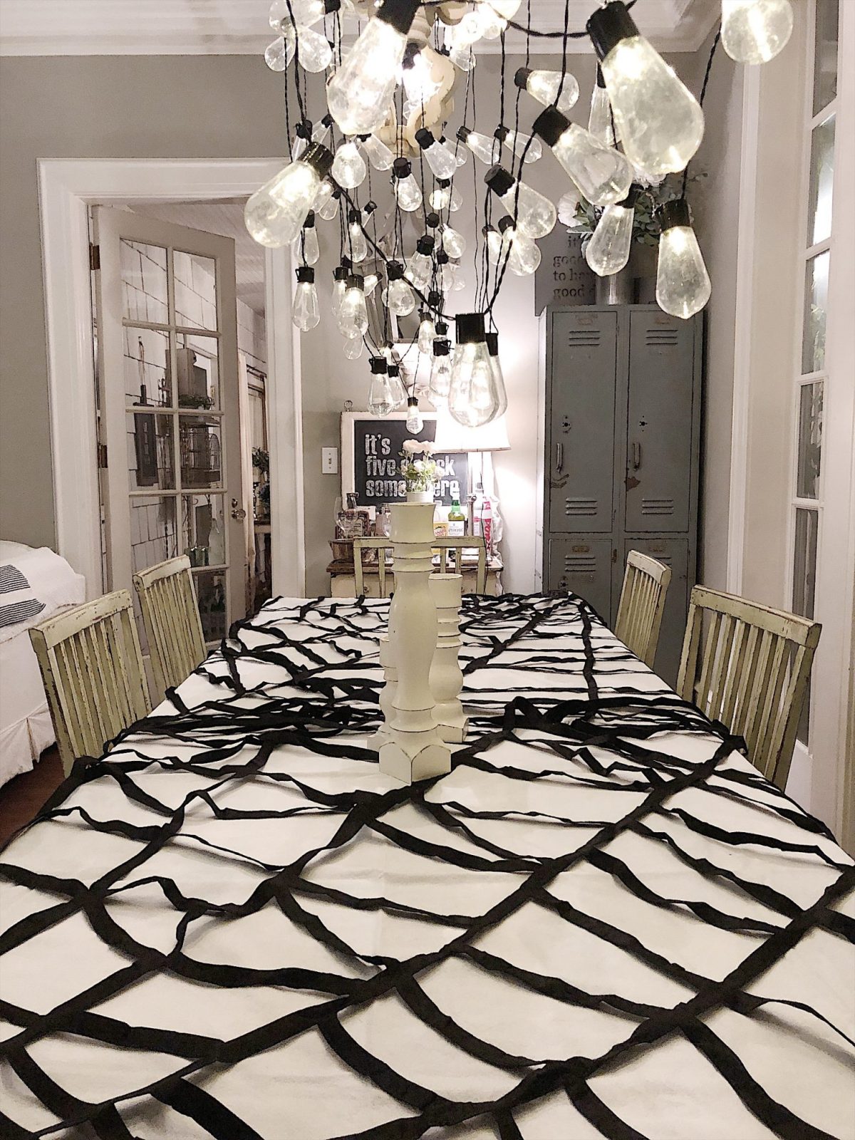 A Halloween table decorated with lights, a spider web, chalkboards, candles, cookies, candy, and more.