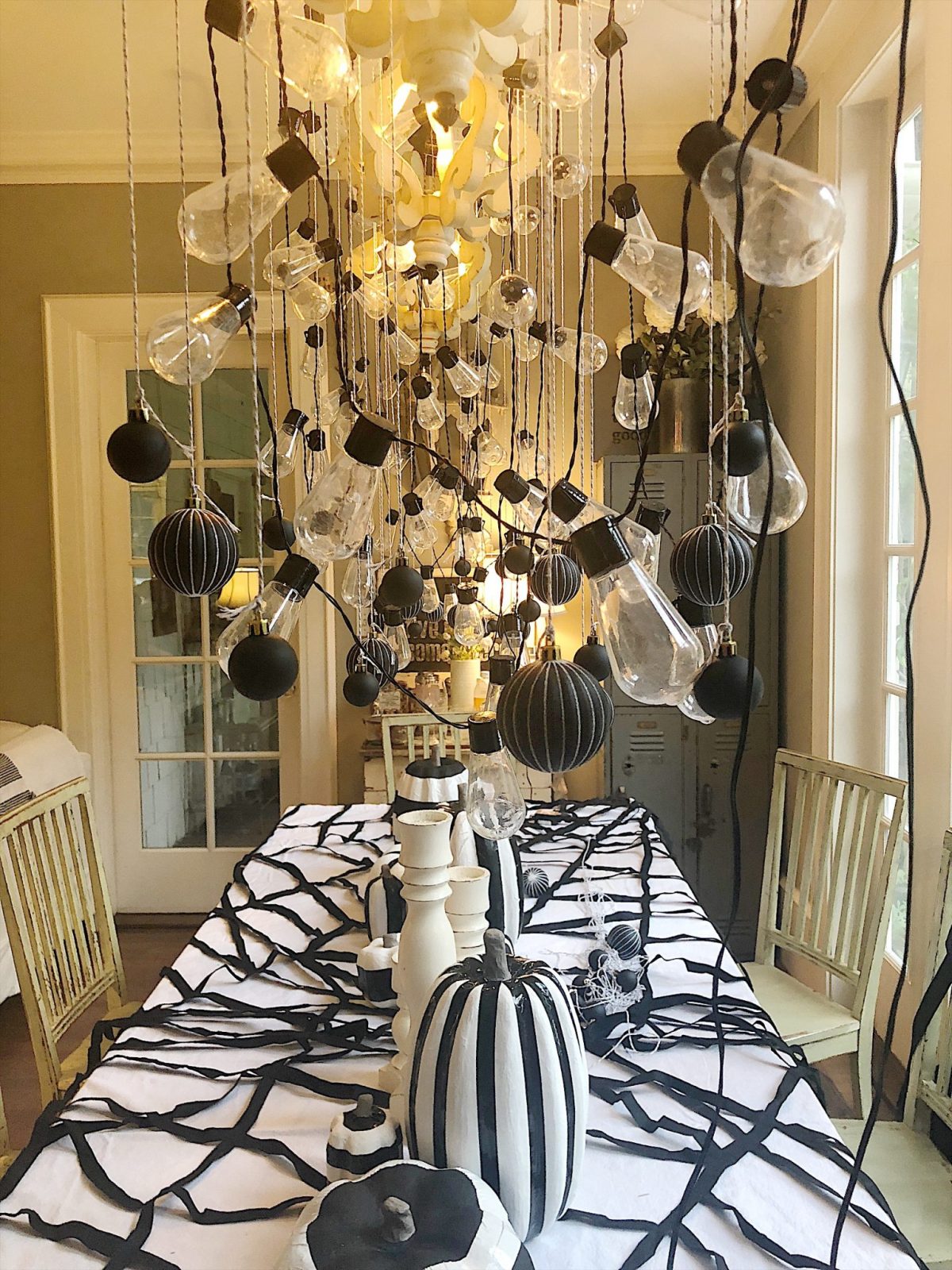 A Halloween table decorated with lights, a spider web, chalkboards, candles, cookies, candy, and more.