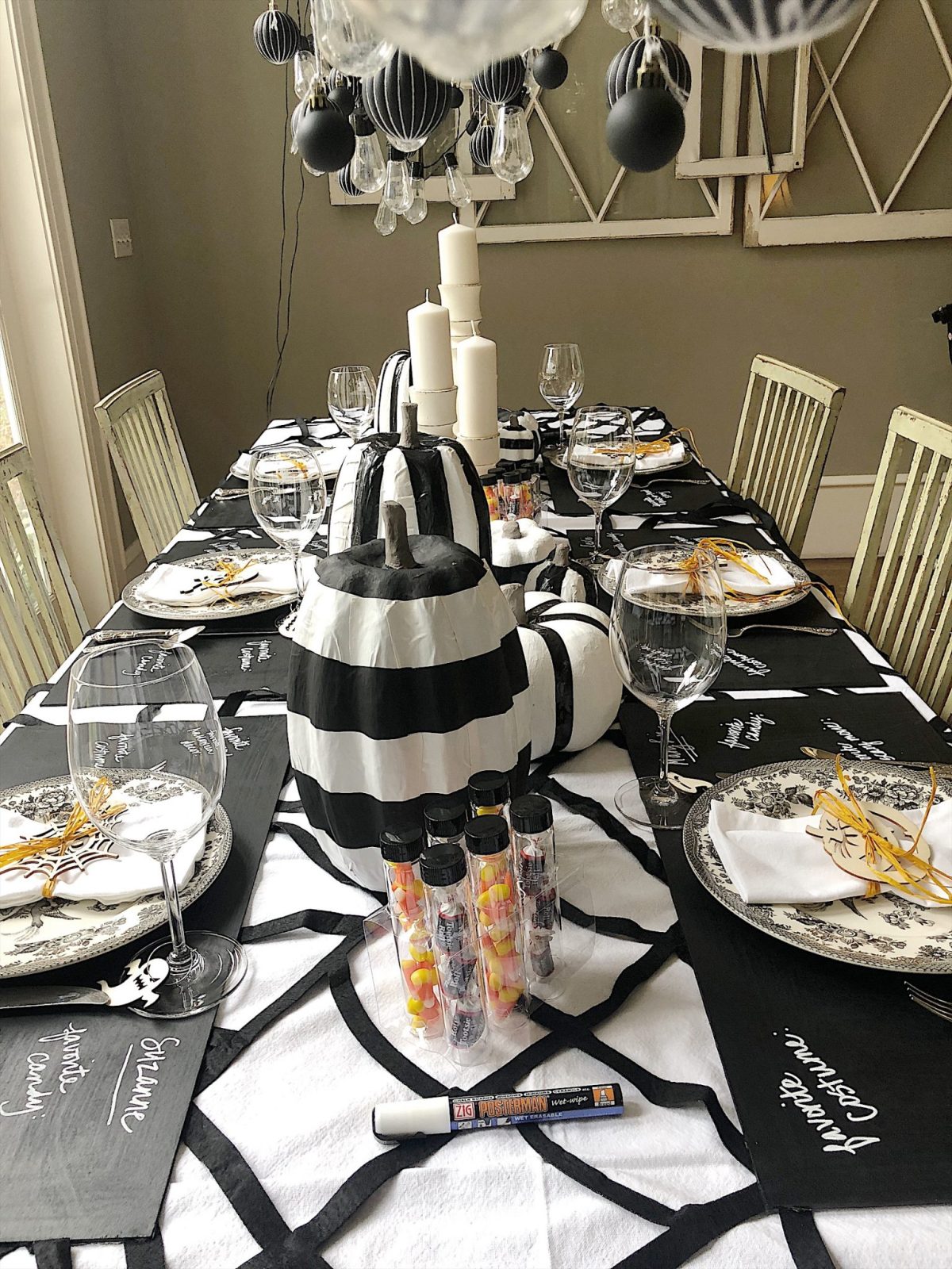 A Halloween table decorated with lights, a spider web, chalkboards, candles, cookies, candy, and more.