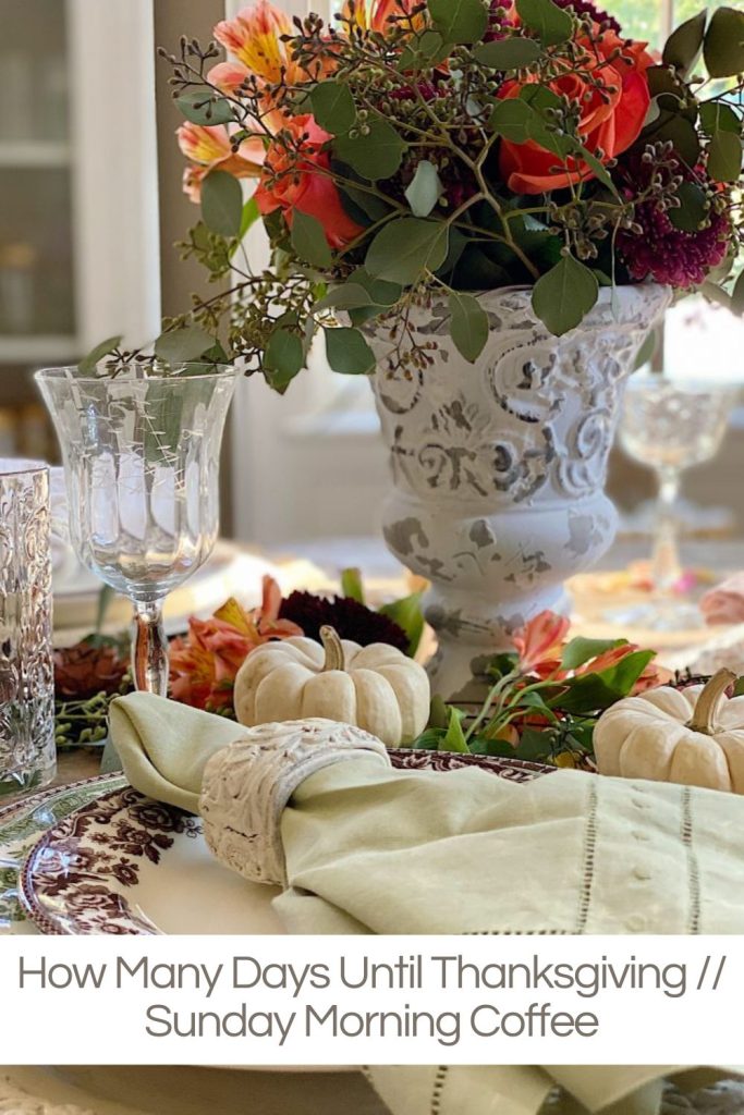 A Thanksgiving table with a white vase with fresh flowers, fall decor, and small pumpkins.