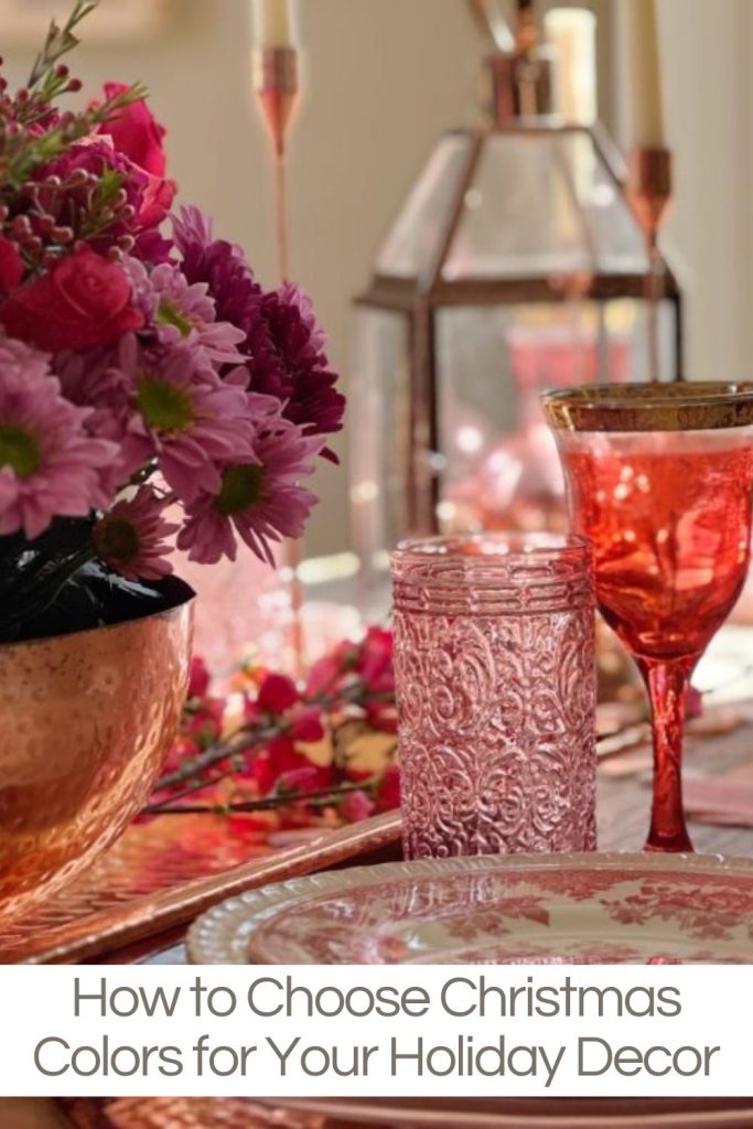 A table set with cranberry dishes and glasses and rose gold bowl, tray, candlesticks, and lantern.