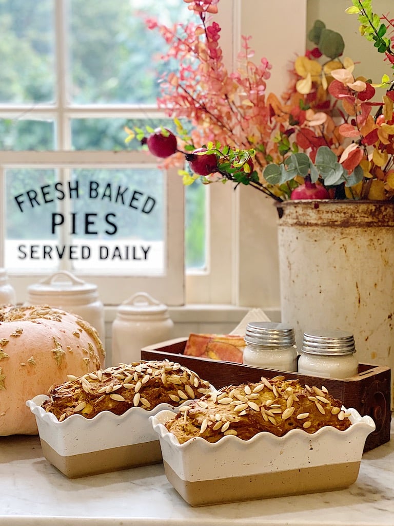 Homemade Pumpkin Banana Bread and Pumpkin Apple Bread in cute bread pans with fall florals in the background.