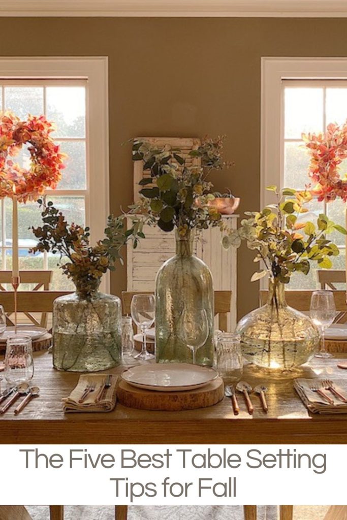 A table set for fall with faux flowers, tall candles, copper accessories and more.