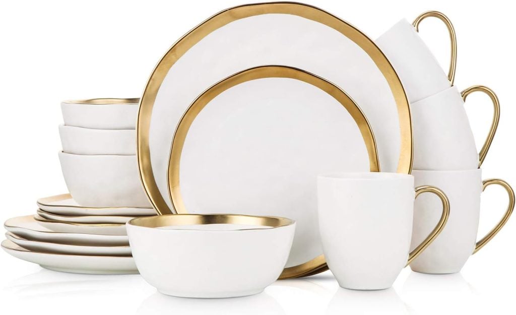 A set of white dishes with gold rims, perfect for setting a festive Christmas table, including plates, bowls, and mugs arranged neatly.