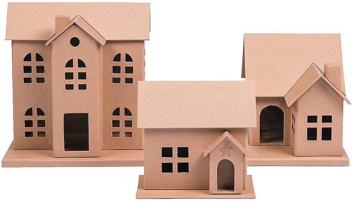 Three small, plain cardboard houses with cut-out windows and doors, resembling Christmas gingerbread houses, are neatly arranged on a flat surface.