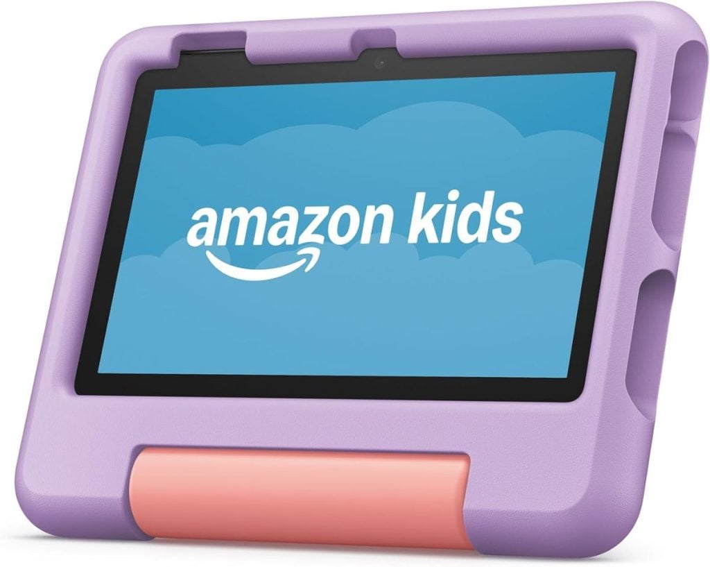 A tablet with a purple case displaying the Amazon Kids logo sits beside a beautifully flocked Christmas tree, creating a festive and tech-savvy holiday scene.