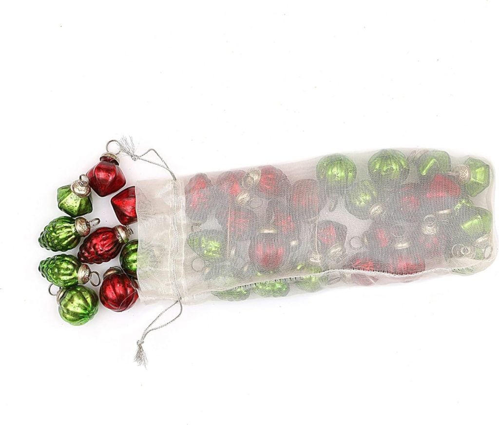 A sheer white bag holds red and green ornaments, perfect for adorning a beautifully flocked Christmas tree.