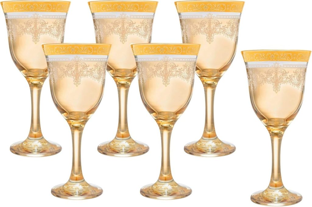 Six ornate gold and clear wine glasses with decorative patterns on the rim, arranged in two rows, perfect to set a festive Christmas table.