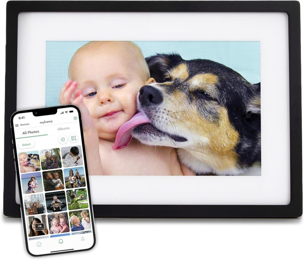 A smartphone displays a photo gallery app, while next to it, a digital frame captures a heartwarming moment of a baby being licked by a dog beneath the glow of a flocked Christmas tree.