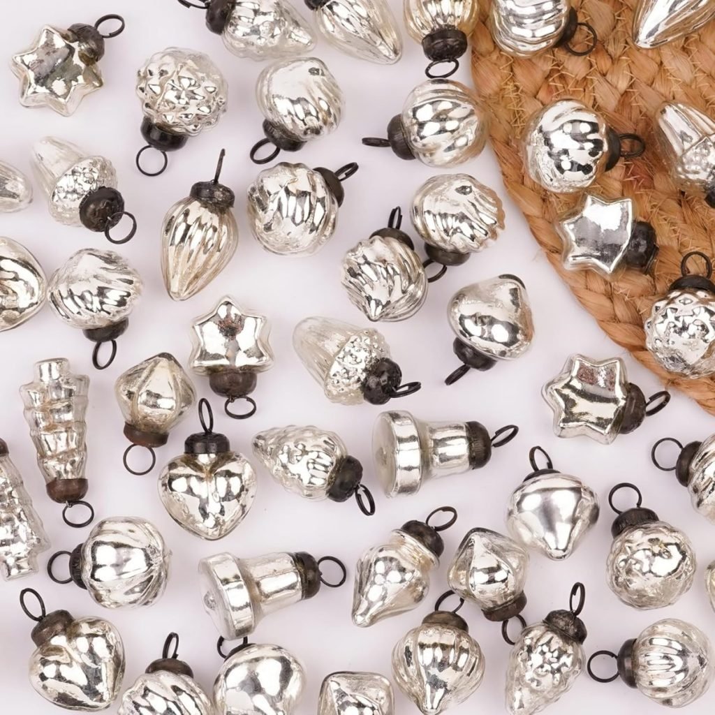 A collection of small, decorative silver ornaments in various shapes, perfect for setting a festive Christmas table, beautifully displayed on a woven mat.