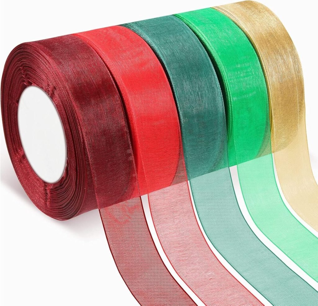 Five rolls of sheer ribbon in maroon, red, green, light green, and gold are displayed partially unrolled—perfect for setting a festive Christmas table with elegance.