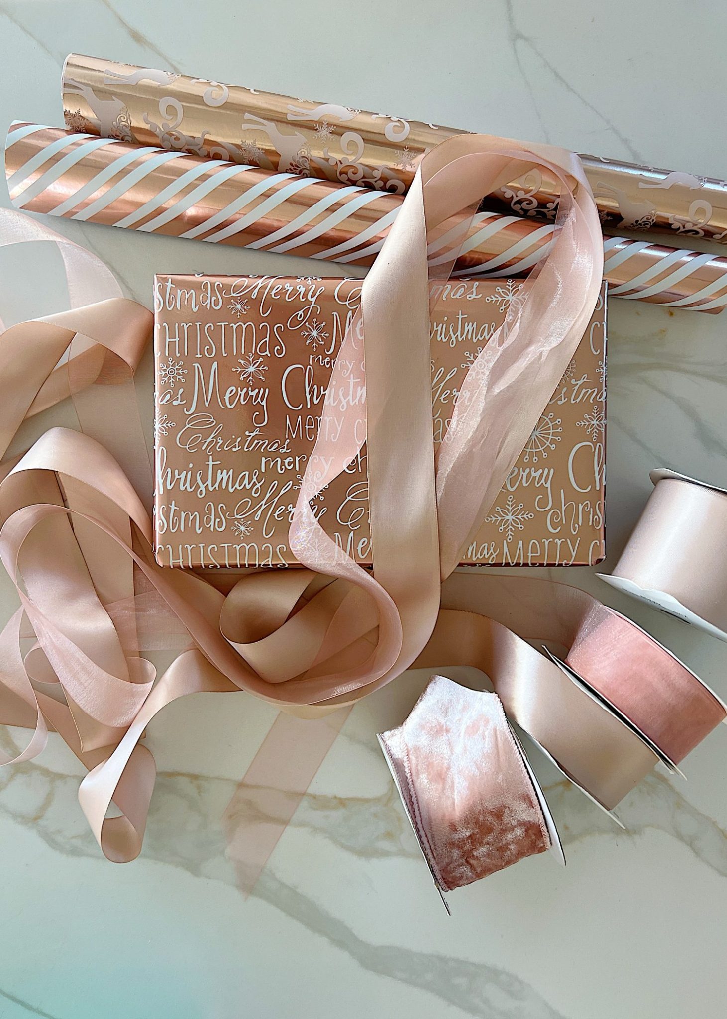 Instructions to tie a bow with ribbon on your Christmas gifts using rose gold metallic wrapping paper and assorted ribbons.