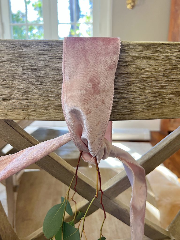 Tying a bow on the back of a dining room chair.