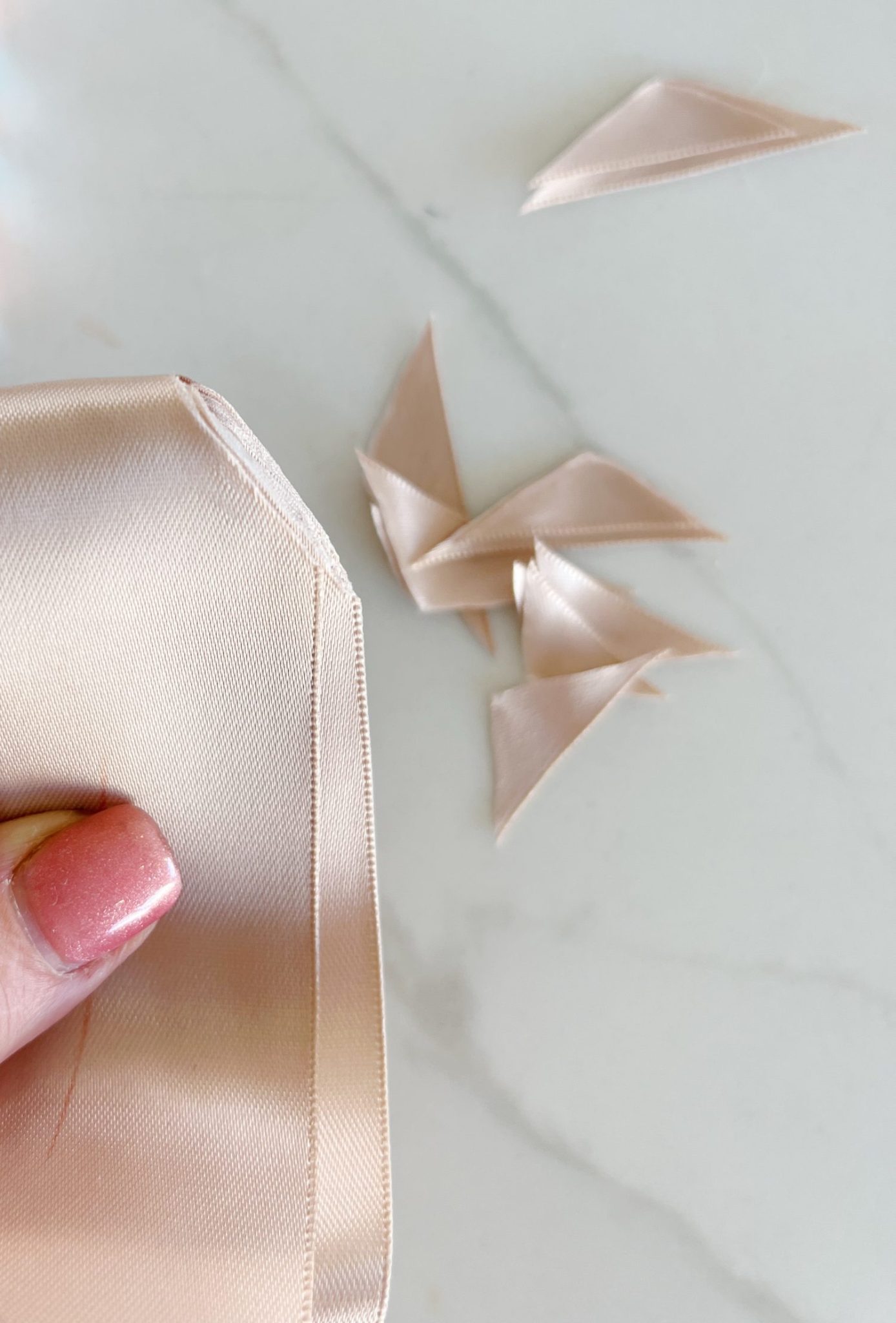 Instructions to tie a bow with ribbon on your Christmas gifts using rose gold metallic wrapping paper and assorted ribbons.