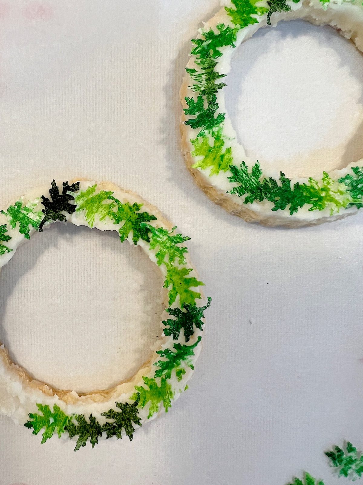 Homemade sugar cookies with buttercream frosting decorated with wafer paper wreaths.