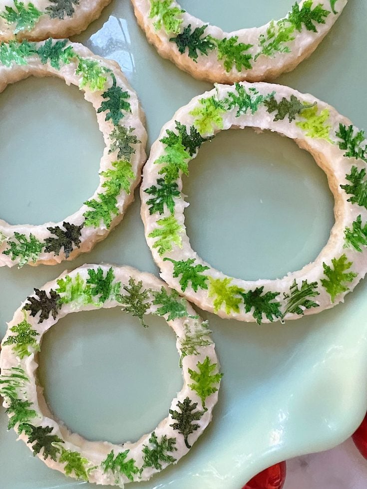 Homemade sugar cookies with buttercream frosting decorated with wafer paper wreaths.