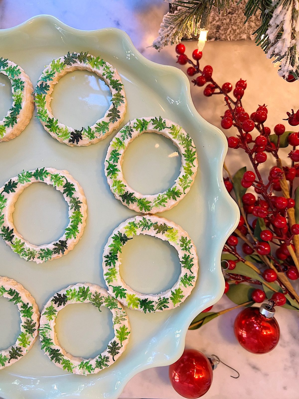 Homemade sugar cookies with buttercream frosting decorated with wafer paper wreaths.