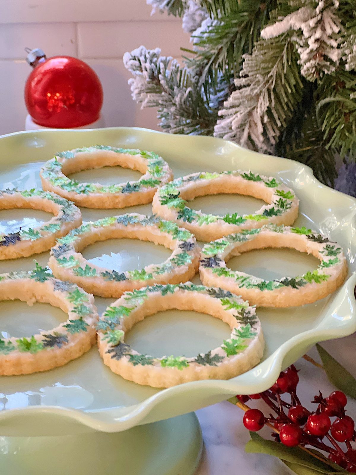 Homemade sugar cookies with buttercream frosting decorated with wafer paper wreaths.
