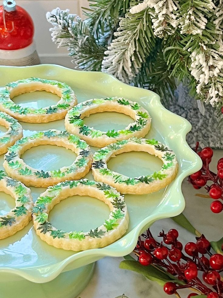 Homemade sugar cookies with buttercream frosting decorated with wafer paper wreaths.