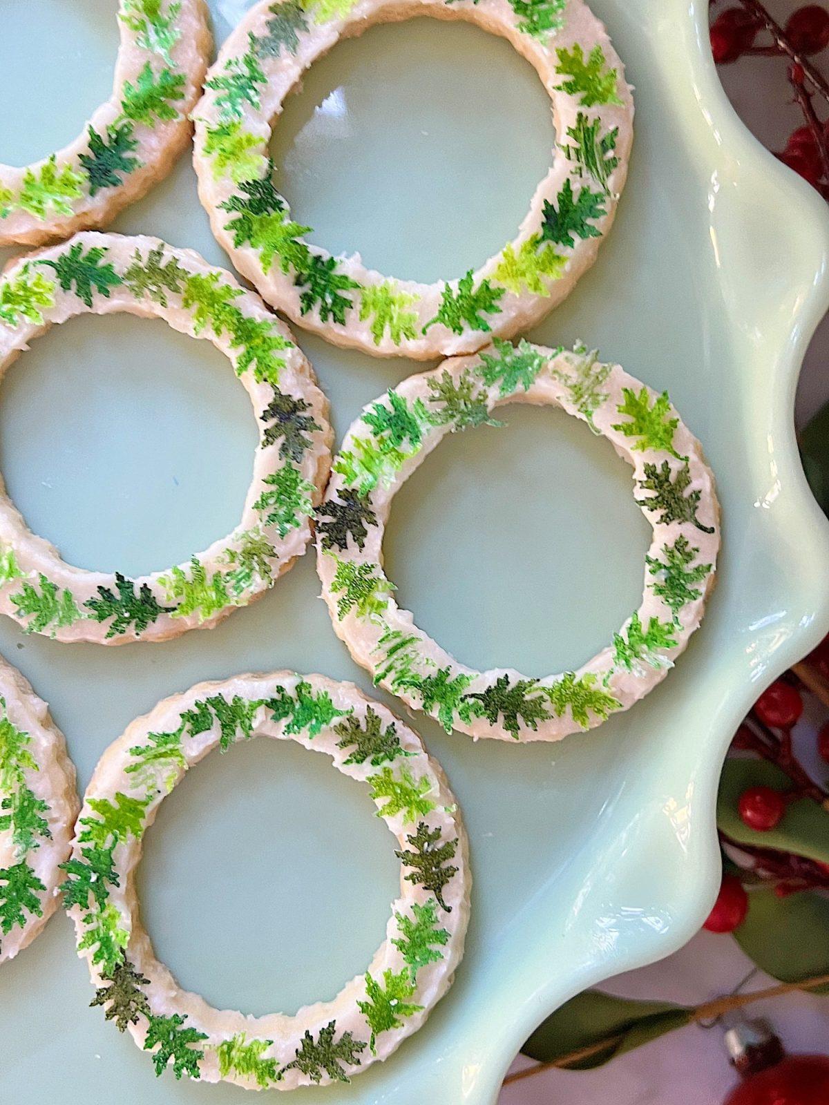 Homemade sugar cookies with buttercream frosting decorated with wafer paper wreaths.