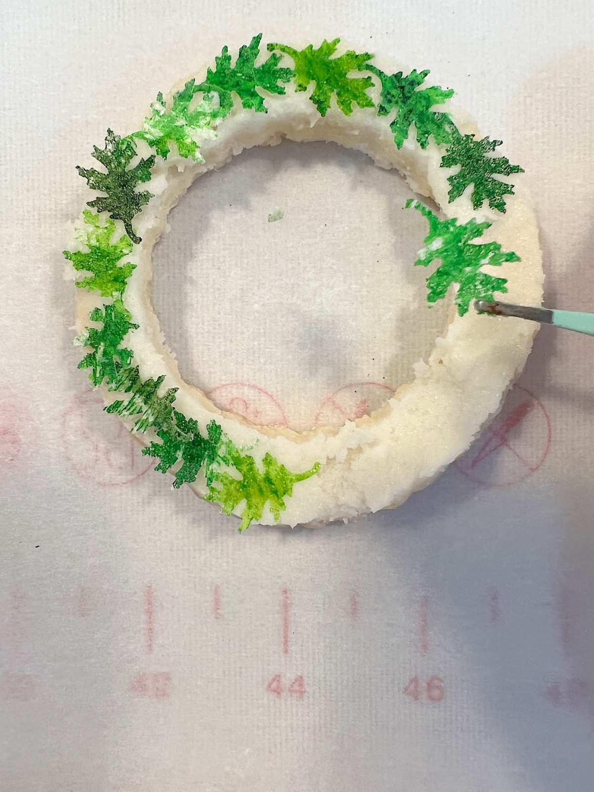 Homemade sugar cookies with buttercream frosting decorated with wafer paper wreaths.