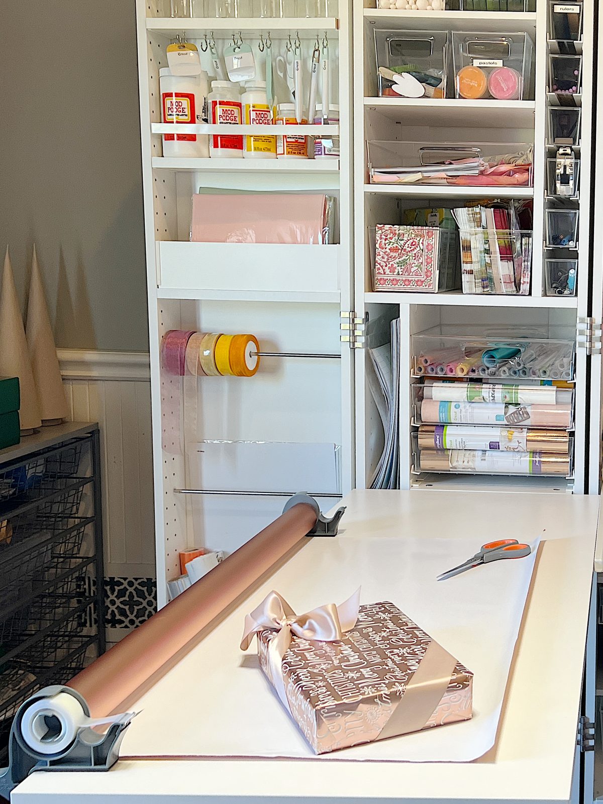 My craft room with a Dream Box filled with craft supplies and a wrapping paper table.