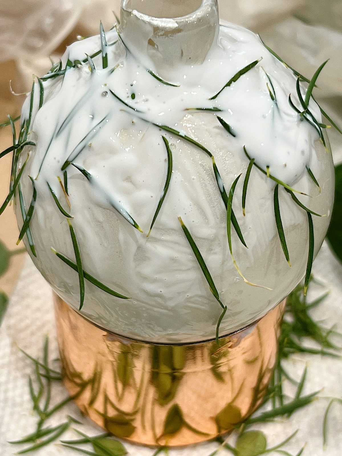 Handmade metallic glass Christmas ornaments made with metallic paint and small pine needles and leaves.