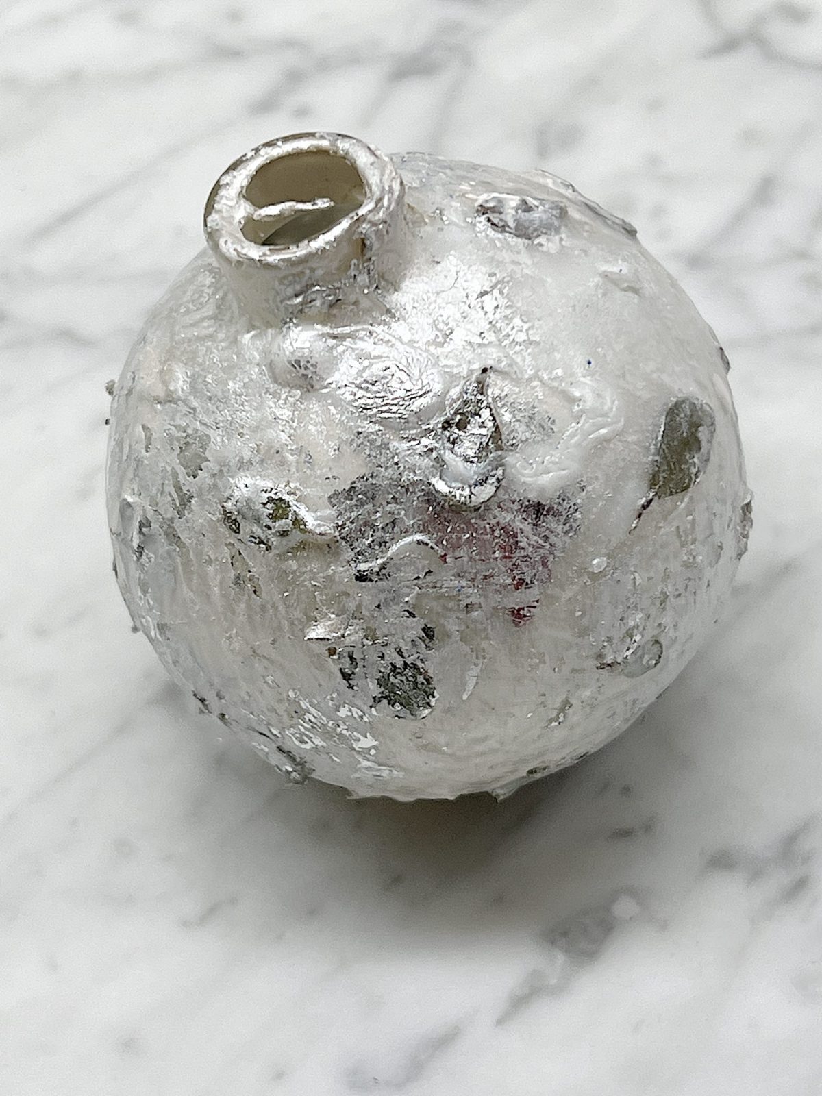 Handmade metallic glass Christmas ornaments made with metallic paint and small pine needles and leaves.