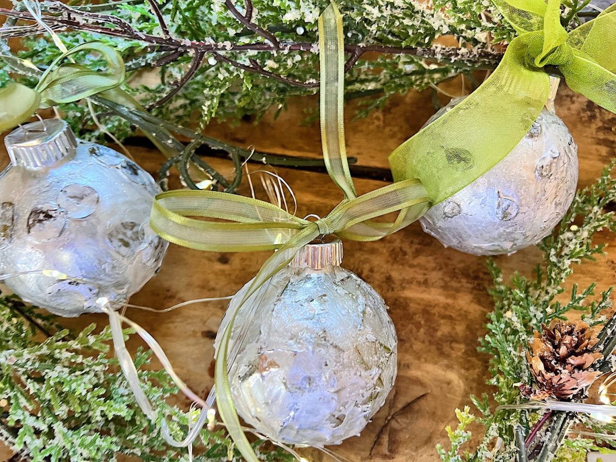 Handmade metallic glass Christmas ornaments made with metallic paint and small pine needles and leaves.