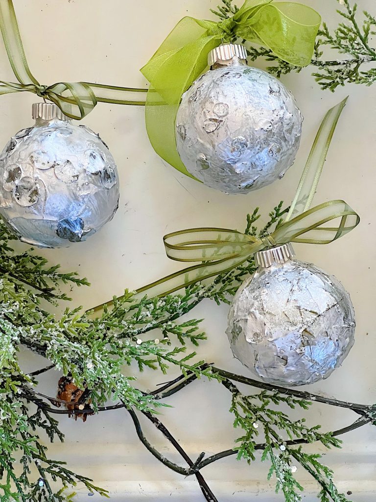 Handmade metallic glass Christmas ornaments made with metallic paint and small pine needles and leaves.