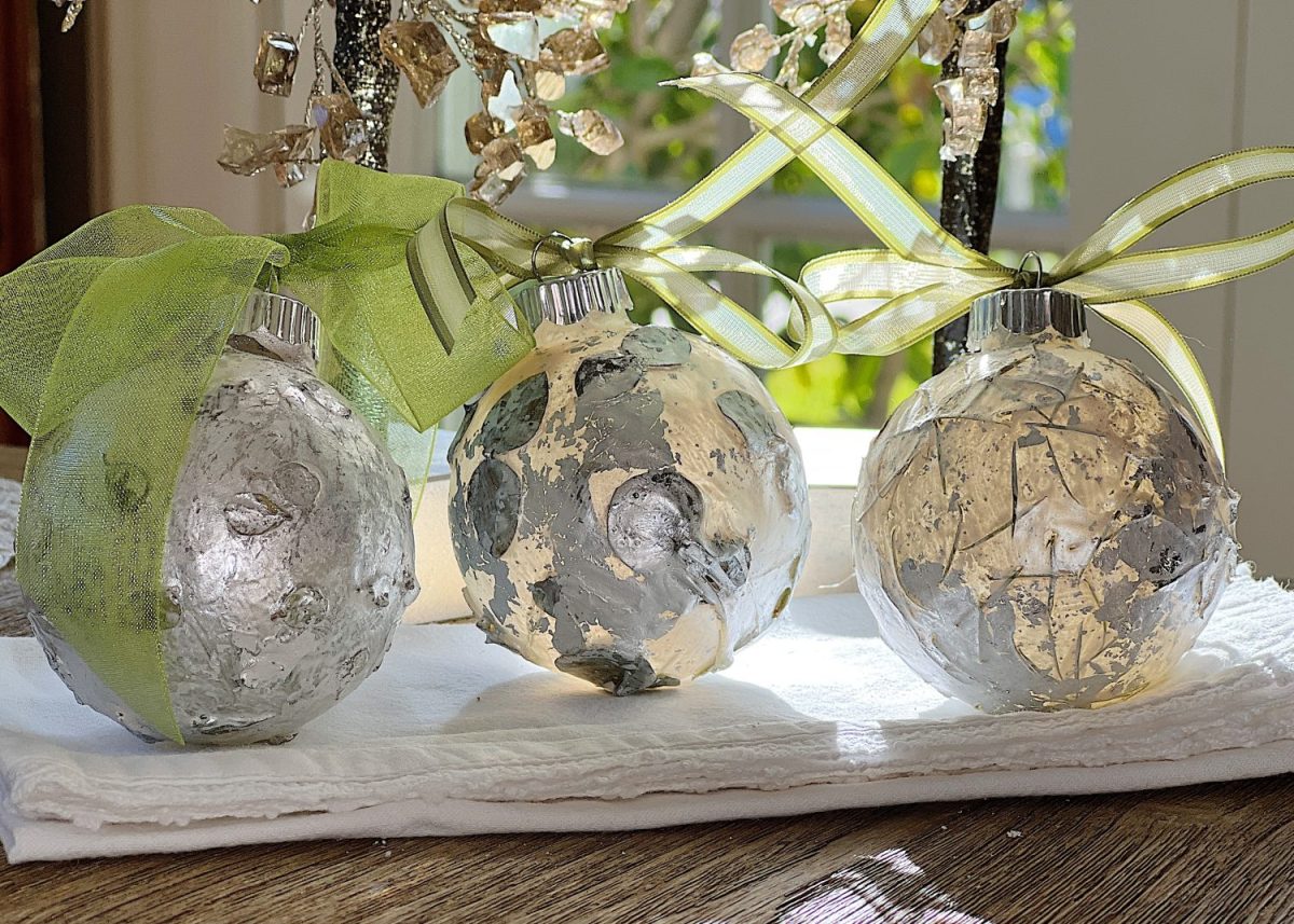 Handmade metallic glass Christmas ornaments made with metallic paint and small pine needles and leaves.