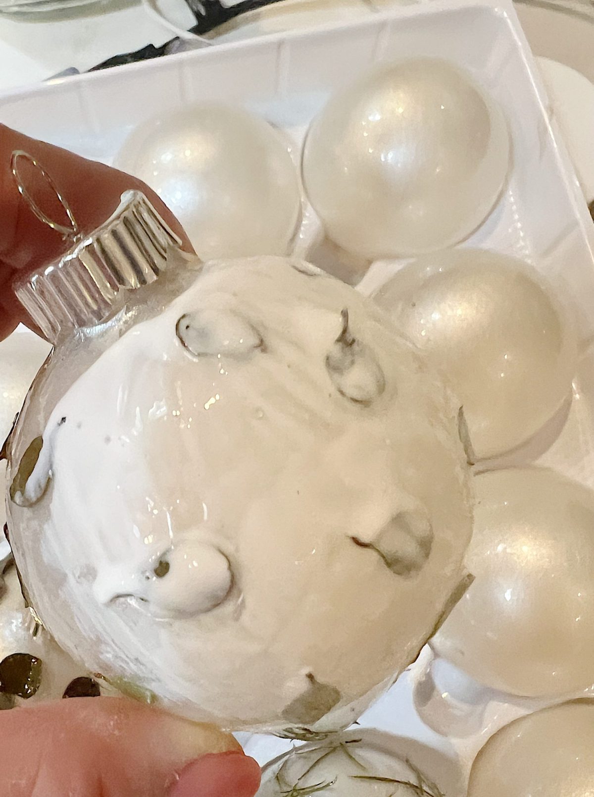 Handmade metallic glass Christmas ornaments made with metallic paint and small pine needles and leaves.