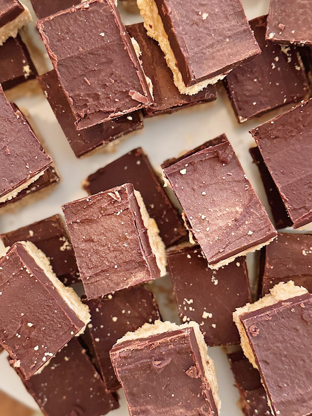 A close-up of chocolate-covered bars arranged on a surface, each with a layer of chocolate and crumbly base, reminiscent of a delectable peanut butter fudge recipe.